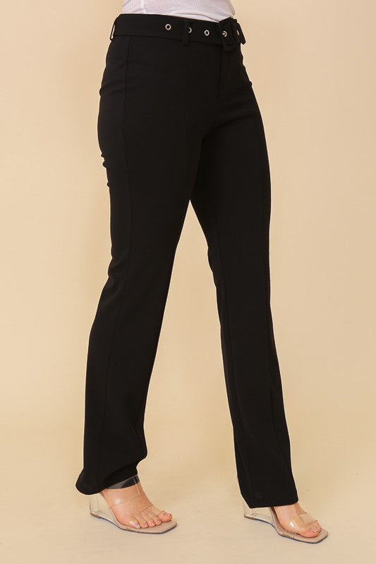 Woman wearing high-waisted black belted straight-leg trousers paired with transparent wedge sandals
