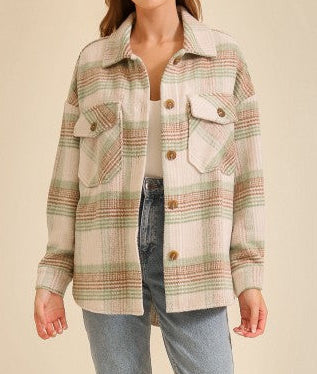 Woman wearing an oversized plaid shacket with front flap pockets paired with light wash blue jeans and a white top