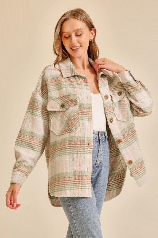 Woman wearing an oversized plaid shacket in cream, green, and brown tones paired with light blue jeans and a white top