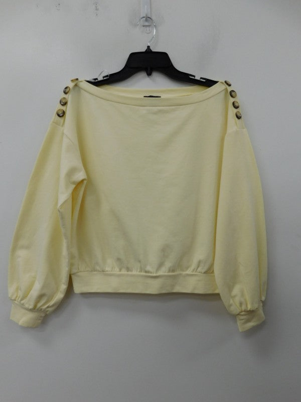 Pale yellow French terry top with button accents on shoulders and gathered cuffs hanging on a black hanger