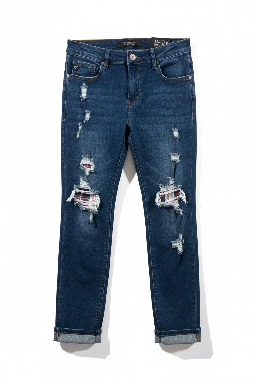 Dark blue mid rise skinny jeans with distressed patches featuring striped fabric accents and rolled cuffs