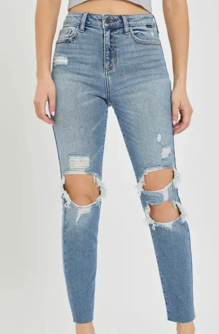 Front view of high rise mom jeans in light blue denim with distressed cutout knees and frayed hems