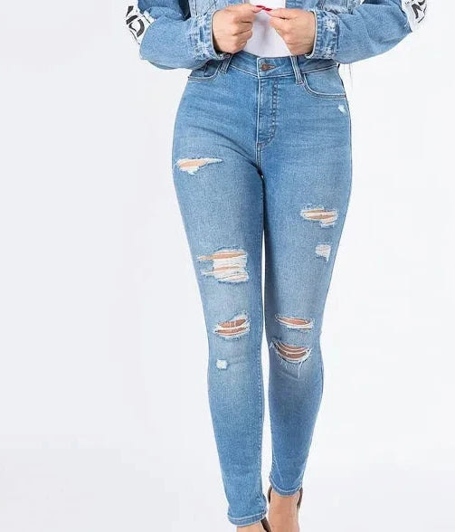 Front view of light blue distressed skinny jeans with multiple ripped patches on a standing model